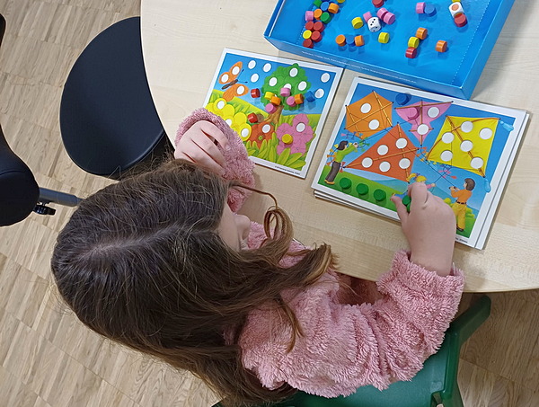 Ein Mädchen sitzt am Tisch und spielt ein Spiel