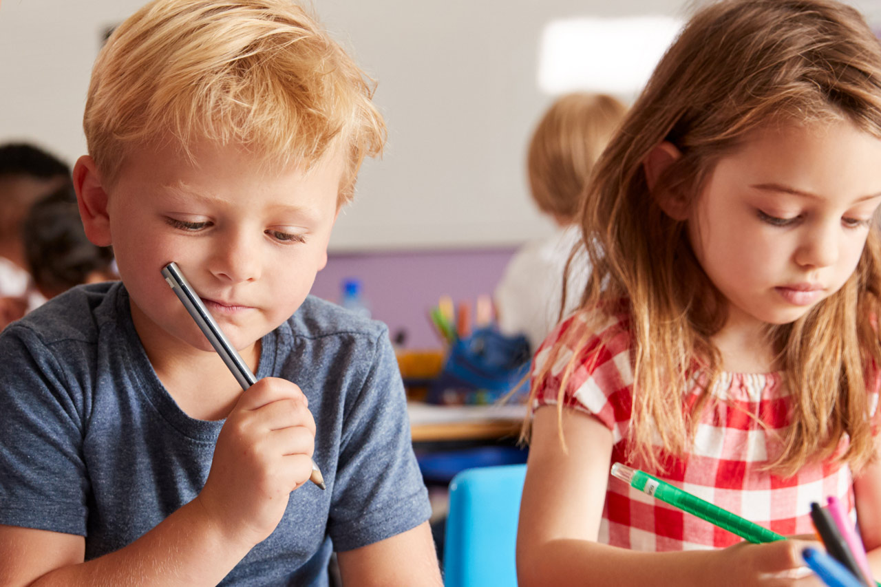 Zwei Kinder beim Schreiben in einer Klasse.