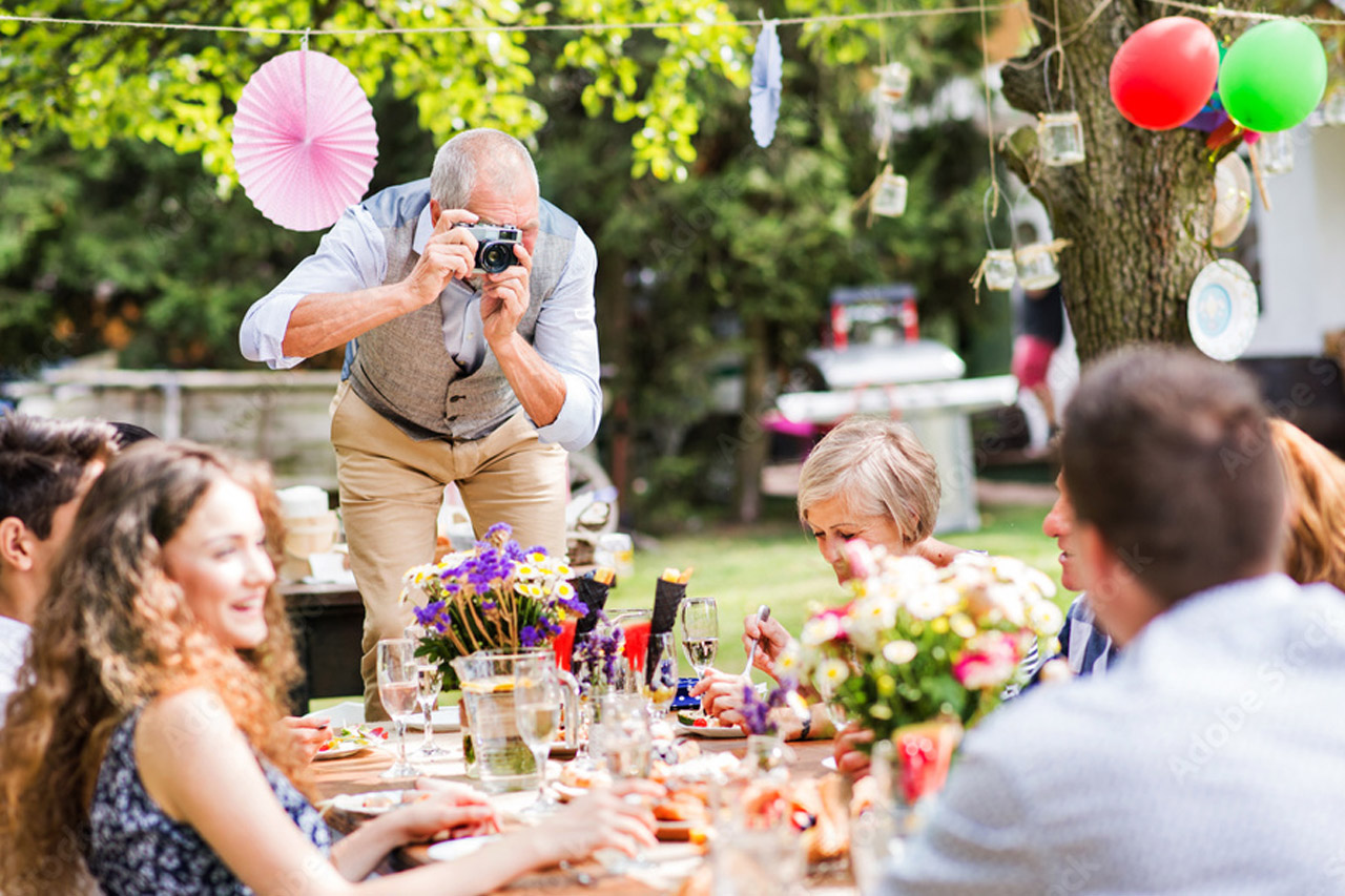 Ein Mann macht ein Foto von einer Gruppe auf einer Gartenparty.