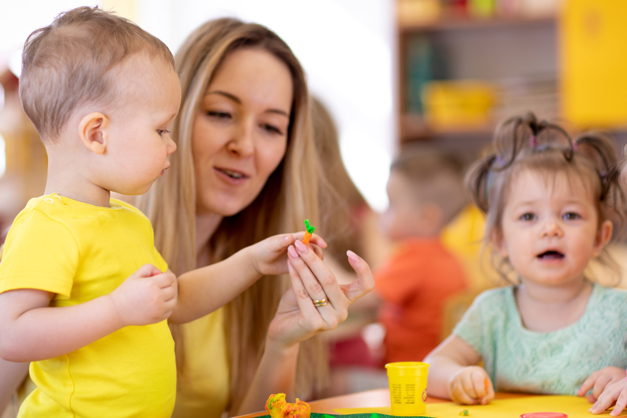 Eine Erzieherin spielt mit zwei Kindern.