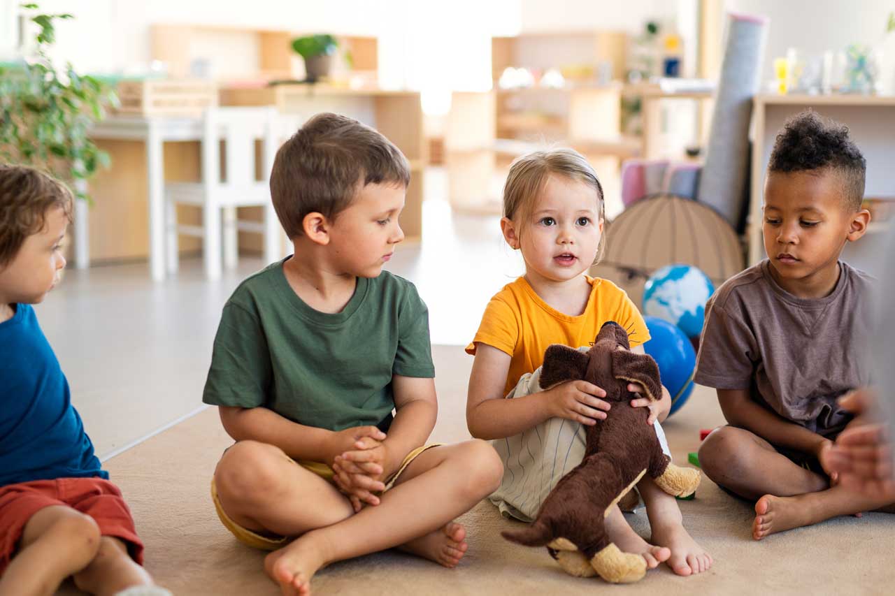 Eine Gruppe Kinder sitzt auf dem Boden und hört zu.