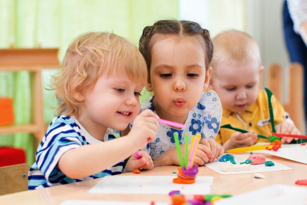 Drei Kinder beim Basteln am Tisch.