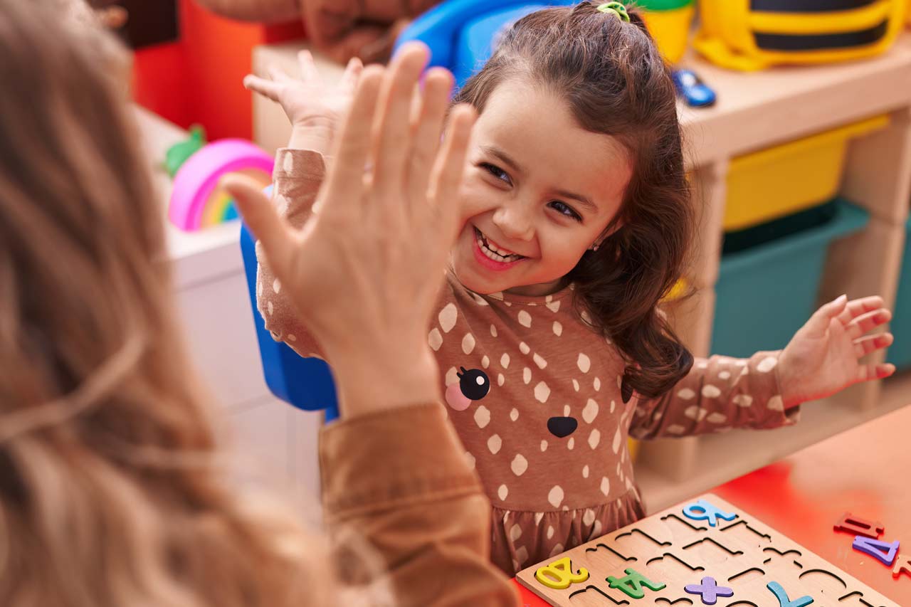 Ein Mädchen schlägt sich mit der Hand mit der Lehrerin ab.