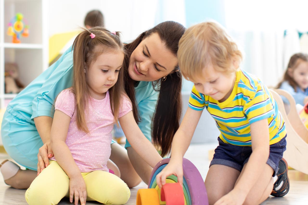 Eine Frau spielt mit zwei kleinen Kindern.