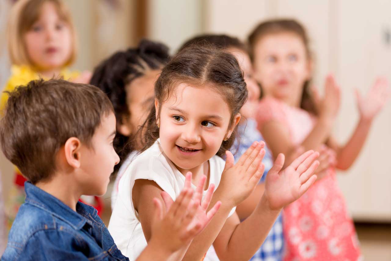 Kinder klatschen rhythmisch in die Hände.